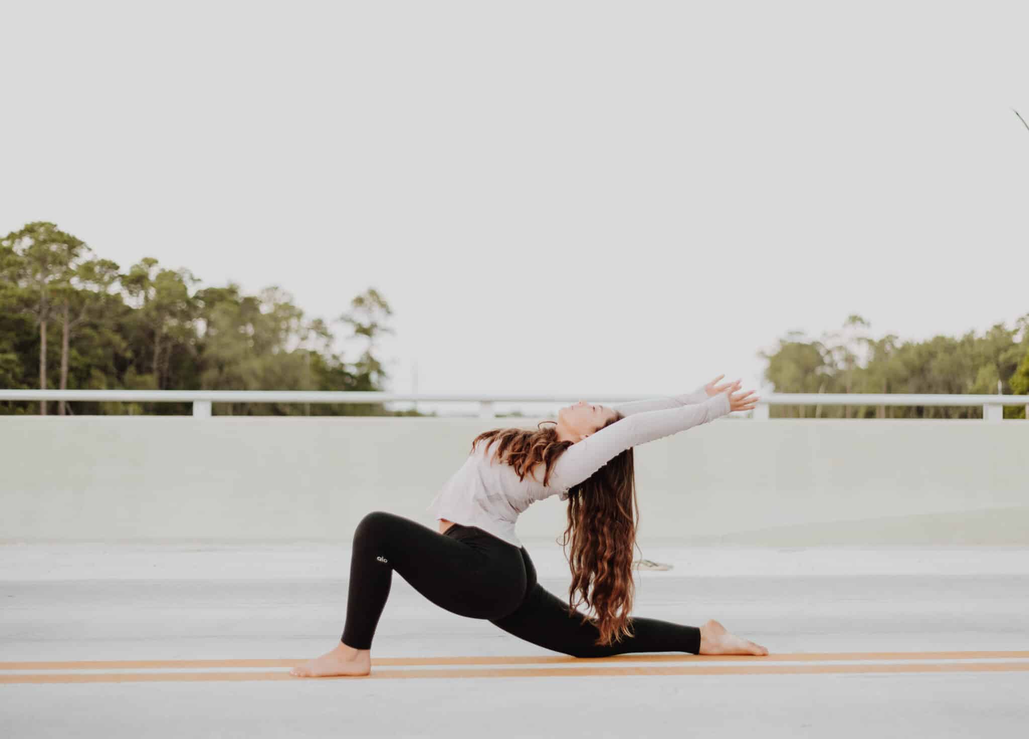 How to Become a Certified Yoga Teacher. A woman doing a forward lunge stretching her arms backwards.